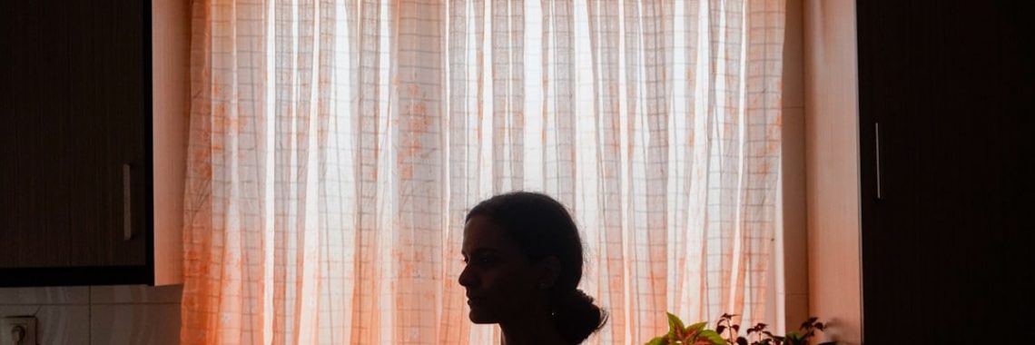 Silhouette of a woman in front of a sunlit window.